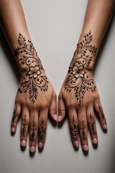 two hands with henna tattoos on them