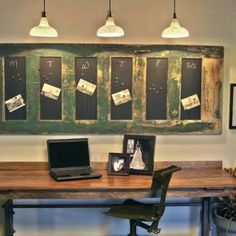 a wooden desk topped with a laptop computer sitting next to a wall mounted chalkboard