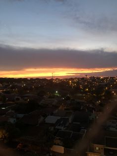 the sun is setting over a city with houses in the foreground and clouds in the background