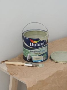 a can of duluxx simply refresh paint next to a brush on a table