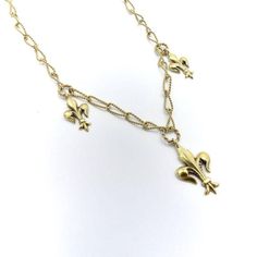 This is part of Chairish’s Fine Jewelry assortment.  A delicate handmade necklace from the Victorian-era, circa 1890, featuring well-sculpted fleur-de-lis. The chain is made from 14k gold wire, which was hand-twisted into elongated oval links, and then twisted again, halfway, reminiscent of a Mobius strip. Suspended from the chain are three fleur-de-lis in descending size, with the largest in the centre of the necklace. Each fleur-de-lis hangs from a wire-twisted round link.  This graceful, femi Victorian Gold Necklace With Figaro Chain, Elegant Brass Chain Necklace With Vintage Charm, Elegant Gold Chain Necklace With Vintage Charm, Victorian Yellow Gold Necklace With Adjustable Chain, Mobius Strip, Feminine Necklace, Elongated Oval, Handmade Chain, Accessories Jewelry Necklace