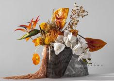 a vase filled with flowers and leaves on top of a table