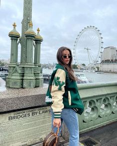 a woman standing on the side of a bridge next to a large ferris wheel in london