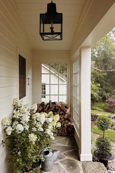 an image of a porch with flowers on the side and firewood stacked in front