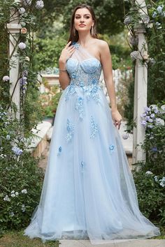 a woman wearing a blue dress standing in front of a flower covered arbor with flowers all around her