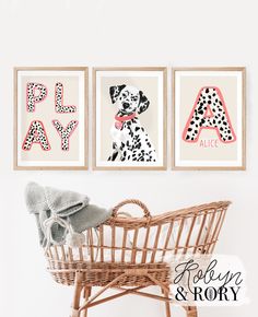 three framed art prints on the wall above a wicker chair with a baby's crib