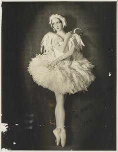 an old black and white photo of a woman in a tutu with feathers on it