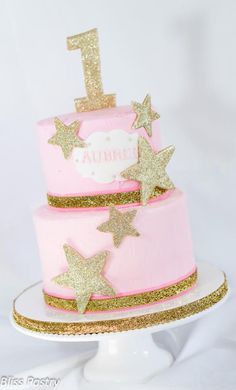 a pink and gold birthday cake with stars on top