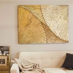 a living room with a white couch and a gold painting on the wall above it