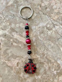 a key chain with a ladybug charm hanging from it's side on a marble surface