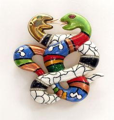 a colorful snake brooch sitting on top of a white surface