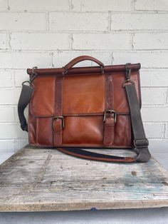 This is a great brown leather satchel. It is a great size to fit most laptops. The front has two buckle straps that have click in brass attachments. There are plenty of pockets inside and out to hold a number of needed cords, pens etc.. This bag has the most wonderful patina to it. It will expand but is about 5" deep without anything in the bag. It has an adjustable strap to wear it as a crossbody. Perfect for a man or woman. The inside is very clean. 16"x12"x5" Vintage Briefcase, Brown Leather Satchel, Vintage Leather Bag, Bag Vintage, Vintage Brown, Leather Satchel, Inside Pocket, Leather Crossbody, A Man