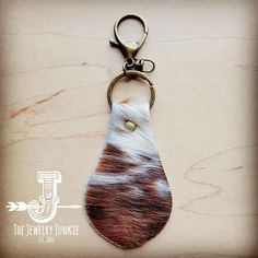 an animal print keychain is hanging on a wooden surface with a metal hook