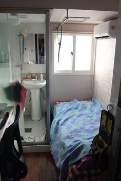 a small bathroom with a bed, sink and mirror