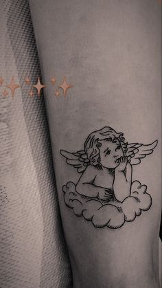 a small tattoo of an angel sitting on top of a cloud with stars in the background