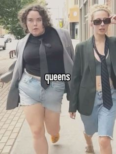 two women walking down the street, one wearing a tie and the other in shorts