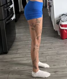 a woman is standing in the kitchen with tattoos on her legs and leggings