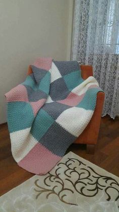 a blanket sitting on top of a wooden chair next to a white and black rug