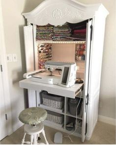 a sewing machine sitting on top of a white desk next to a cabinet filled with fabric