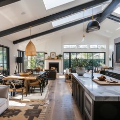 a large open concept kitchen and dining room with wood flooring, white walls and black beams