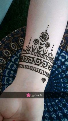 a henna tattoo on someone's wrist that is decorated with flowers and leaves