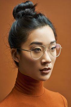 a woman wearing glasses and an orange turtle neck sweater