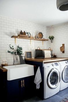 a washer and dryer in a small room with white tiles on the wall