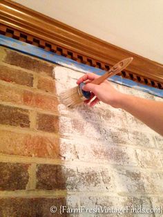 a person is painting a brick wall with a brush and paint roller in their hand