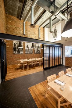 an empty dining room with wooden tables and chairs in front of a brick wall that has pictures on it