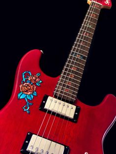 a red electric guitar with an embroidered rose on it