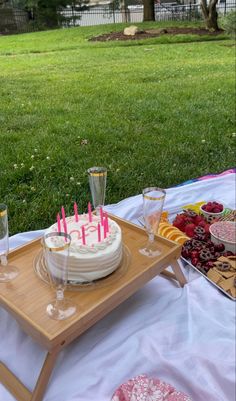 a birthday cake sitting on top of a wooden tray next to other desserts and drinks