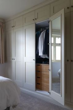 a bedroom with a bed, closets and curtains on the window sill in front of it