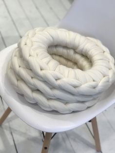 a white chair sitting on top of a wooden floor next to a pile of rope