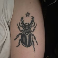 a black and white beetle tattoo on the right arm, with a star in it's center