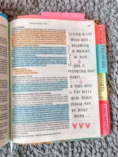 an open bible on the ground with colored paper and writing in each section, which includes words from different countries