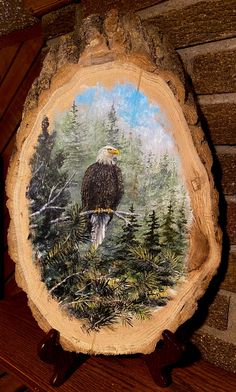 an eagle sitting on top of a tree stump with pine trees in the back ground