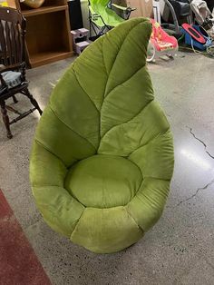 a green bean bag chair sitting on the floor in a room with other furniture and chairs