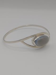 A silver bangle with a blue/grey stone, made in 1961 by Gussi, Malmö, Sweden. The bangle is in excellent condition. The bangle is fully hallmarked Handsmide/handcrafted, Gussi, M for the town mark of Malmo, cat paw, S for silver and L9 for the year 1961. Measurements The diameter of the bangle is 7 cm The stone is 2.5 cm in length  The stone is 1.5 cm in diameter  Weight 14 grams Silver Oval Cuff Bracelet With Polished Finish, Modern Silver Oval Bangle, Silver Oval Bangle With Polished Finish, Modern Formal Gemstone Bangle, Formal Silver Oval Cuff Bracelet, Sterling Silver Modernist Bangle, Modern Silver Gemstone Bangle, Modern Silver Bangle With Gemstone, Modernist Silver Bangle With Polished Finish