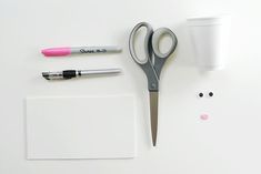 a pair of scissors, pens and markers on a white surface