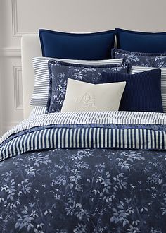 a bed with blue and white sheets and pillows