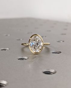 a diamond ring sitting on top of a metal surface with holes in the floor behind it