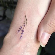 a woman's foot with a small flower tattoo on her left ankle and purple flowers in the middle