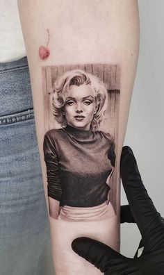 a woman's arm with a marilyn monroe tattoo on it