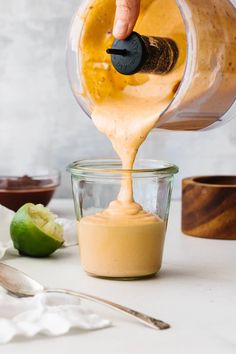 someone pouring sauce into a small glass bowl