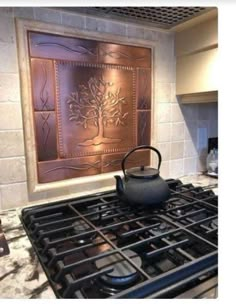 a tea kettle sitting on top of a stove next to a wall with an art work