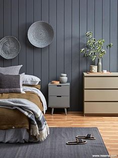 a bed room with a neatly made bed and two planters on the wall next to it