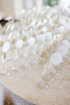 many wine glasses are lined up on a table with place cards in the glass holders