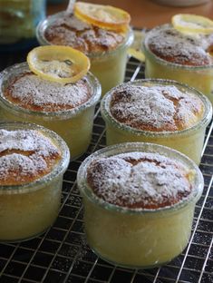 several desserts are sitting on a cooling rack with lemon slices and powdered sugar