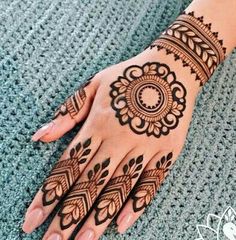 a woman's hand with henna tattoos on her left arm and the top half of