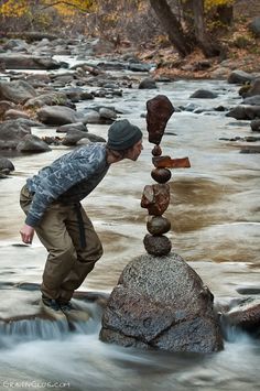 a man balancing rocks on top of a river